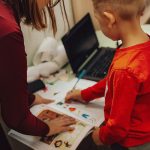 Teacher assisting a child with educational activities in a learning environment.