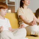 Family practicing meditation together on a couch, promoting mindfulness and relaxation.